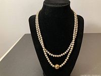 Full view of the double strand sterling silver beaded necklace with gold tone bead on lower strand displayed on black bust stand.