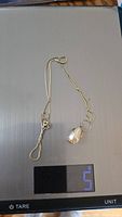 Photo showing the necklace with pendant on a scale displaying weight of 5 grams.
