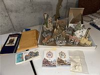 Box with multiple cottage figurines arranged inside. Includes detailed multi-structure pieces and leaflet pamphlets from David Winter.