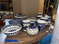 Wide shot of the entire assortment of bowls, mugs, teapots, and serveware on a table.