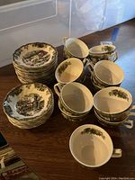 Photo showing stacks of saucers and bowls alongside teacups with detailed countryside village design.