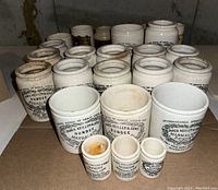 Overall view of approximately 19 stoneware marmalade jars in rows on cardboard