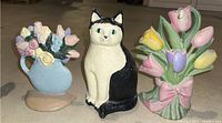 Front view of blue pitcher with flowers, black and white cat, and floral bouquet with tulips door stops.
