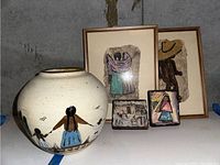 Pottery vase with painted figures alongside four pieces of wall art depicting Midwest and Mexico themes arranged against a concrete wall