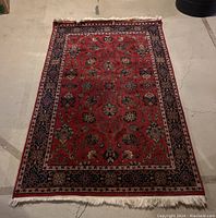 Full view of the 4x6 oriental rug laid flat on a concrete floor with visible intricate floral patterns and red color field.