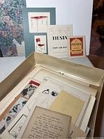 Overview of box containing mounted sketches and loose vellum and paper sheets with drawings and ephemera.
