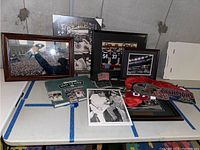 Overview of the sports memorabilia items including framed photos, books, jerseys, caps, and cards on a table in a basement.