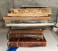 Stack of worn vintage books showing various aged bindings, some with hard cloth and leather covers.