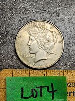 Front side of 1925 US Silver Peace Dollar, showing Lady Liberty with date 1925 and partial measurement ruler for scale.