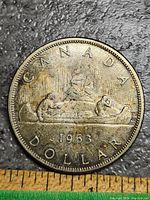 Obverse of the 1963 Canadian silver dollar showing Voyageur design with two men in canoe and the year 1963, tarnished condition
