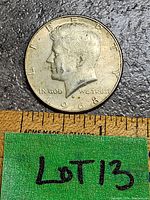 Obverse side of the 1968 Kennedy Half Dollar coin showing Kennedy's profile, inscriptions 'LIBERTY', 'IN GOD WE TRUST', and the year 1968 with a measuring ruler below for scale.