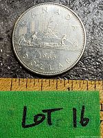 Obverse side of a 1985 Canada Voyageur dollar coin showing the voyageur and Indigenous person in a canoe with the year 1985 and inscription CANADA DOLLAR.