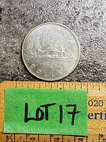 Reverse side of 1985 Canada Dollar coin showing Voyageur design with two canoeists and inscriptions including year and denomination, placed on a measuring ruler.