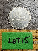 Reverse side of 1985 Canadian Voyageur dollar coin showing the voyageur and Indigenous paddler in a canoe, with 'CANADA 1985 DOLLAR' text visible. Coin is silver-toned with signs of tarnish.