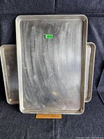 Two stacked aluminum baking trays of size 18x26 inches with visible use marks and dull surface.