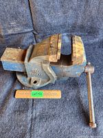 Side view of heavy cast vise with visible 'Made in England' mark and measuring ruler placed under the jaws showing size approximately 4 inches.