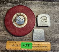 Lot showing vintage Lufkin 100' steel tape in red leather case, Lufkin 10' retractable tape, square metal piece, and wooden ruler with lot number.