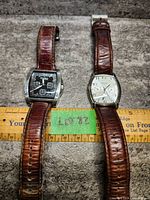 Pair of men's Caravelle by Bulova watches lying flat, showing leather bands and dial faces, with ruler for scale.