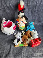 Full lot showing Disney Goofy plush drummer, blue Ty bear, Dalmatian, moose, elephant and Hello Kitty fabric basket