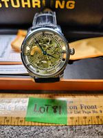 Full view of watch face showing round case and black leather strap, with ruler for scale and Lot 181 tag visible.