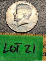 Obverse side showing Kennedy profile with 1776-1976 dual date and signature on surface.