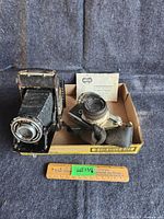 Overview showing two cameras side by side in a cardboard box with a ruler placed below.