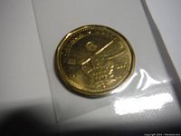 Close-up of a gold-colored commemorative coin featuring a hockey player and Toronto Maple Leafs logo, sealed in plastic.