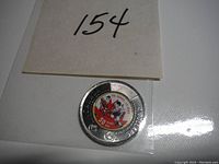 Close-up of the colored twoonie coin showing the 50th anniversary Summit Series design with ice hockey players and a red maple leaf, in plastic sleeve.