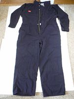 Full view of navy blue coveralls laid flat showing front zipper and pockets