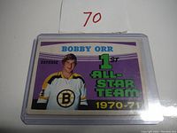 Front view of Bobby Orr 1970-71 vintage hockey card in plastic sleeve, showing player image, team logo, and All-Star designation
