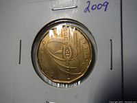Close-up photo of the 2009 Montreal Canadiens 100th Anniversary loonie coin in protective cardboard holder showing coin design details and '2009' handwritten year mark.