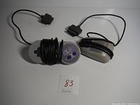 Photo showing SNES controller and mouse with cords, controller has purple buttons and cords coiled