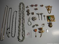 Photo showing all assorted vintage costume jewelry items spread on a light surface including necklaces, earrings, brooches, rings, and pins with a note labelled 31.