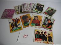 Pile of approximately 40 New Kids on the Block trading cards and stickers from 1989, laid out on a white surface showing front designs with members Donnie, Joe and group images