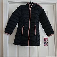 Front view of the girls black Glacier Reebok puffer coat hanging, showing pink zipper and pocket accents, hood, and size small (7/8).