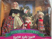 Full set in original packaging showing all three dolls with Christmas tree background and visible box damage