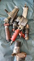 Photo of assorted air tools showing air drill, air grinder, air sander and other attachments on a cloth surface