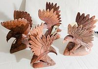 Photo showing the full lot of four hand carved wooden eagles with wings extended on bases.
