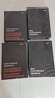 Four black Nike branded boxes labeled Performance Swimwear and Nike Performance Swimwear.