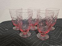 Six pink crinkle glasses grouped together showing the textured pattern and pedestal bases.