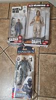 Photo of Walking Dead Sasha figure, Walking Dead Daryl figure, and Halo 5 Spartan Locke figure in packaging.