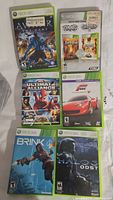 Top view of 6 Xbox 360 game cases including Avatar The Game, Samurai Warriors 2, Ultimate Alliance 2, Forza Motorsport 2, Brink, and Halo 3 ODST.