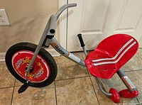 Side angle of Razor Flashrider 360 trike showing front wheel, frame and red molded seat with white stripes.