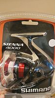 Front view of Shimano Sienna 4000 fishing reel in clear blister packaging showing reel details and branding