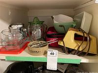 Vintage yellow MixMaster electric hand mixer, assorted glassware including Fire King measuring cups, green juicer, Anchor Hocking bakeware and bowls