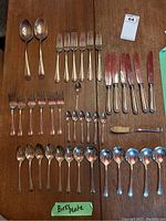 All 41 silver-plated pieces laid out on a wooden table