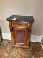Front view of the wood cabinet with green marble top resting on it.