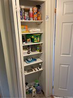 Shelf with numerous cleaning bottles, powders, spray cans and rubber gloves.