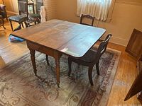 Dining table with double drop leaves folded down, showing drawer in apron and one chair nearby.
