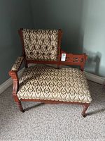 Full view of the Eastlake telephone chair showing wooden frame, patterned upholstery, armrest and wheels.